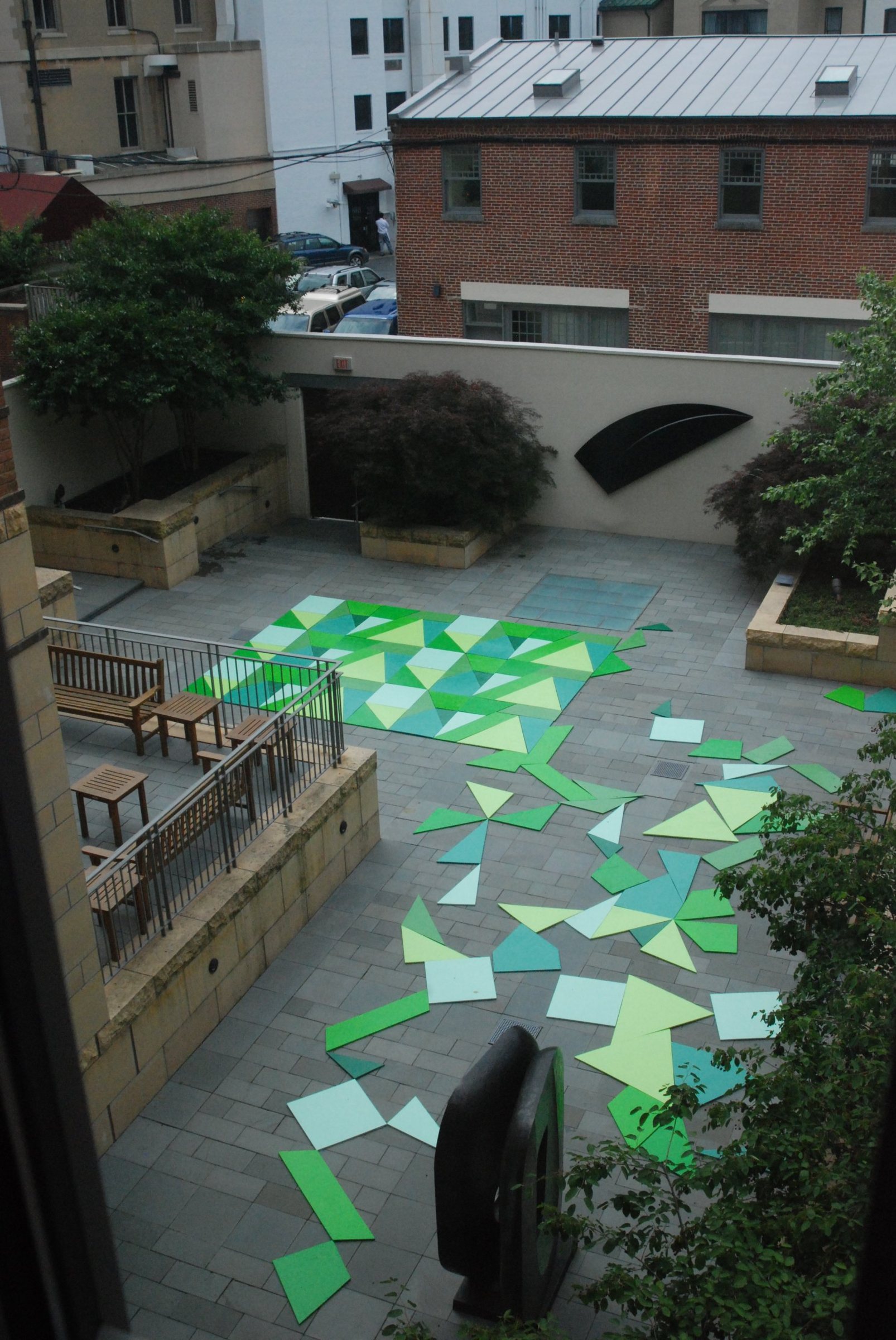 A tall view from a window of the assembled puzzle and scattered pieces, with brick buildings beyond